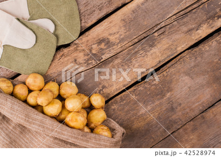 Ripe young potatoes in a burlap bag and mittens. 42528974