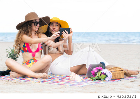 Happy women taking photo on sand beach in summer. Happy women taking photo on sand beach in summer. 42530371