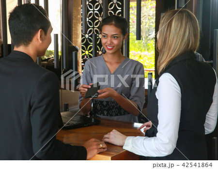 Couple and receptionist at counter in hotel.  42541864