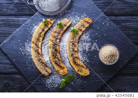 Sweet fried banana served on a black slate board 42545081