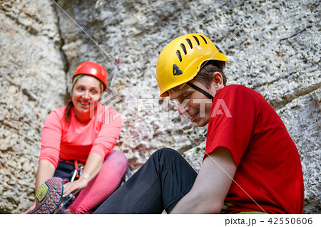 Photo of smiling sports man and woman dressing shoes at cliff 42550606