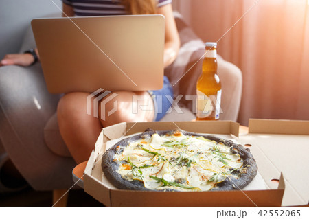 Young woman working on laptop with delivered pizza Young woman working on laptop with delivered pizza 42552065