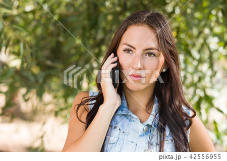 Unhappy Mixed Race Young Female Talking on Cell Phone Outside Unhappy Mixed Race Young Female Talking on Cell Phone Outside 42556955