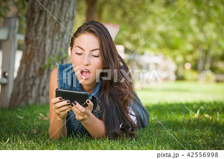 Shocked Mixed Race Young Female Texting on Her Cell Phone Outsid 42556998