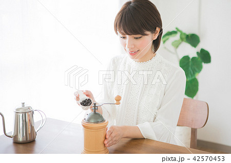 コーヒーミルにコーヒー豆を入れる女性 42570453