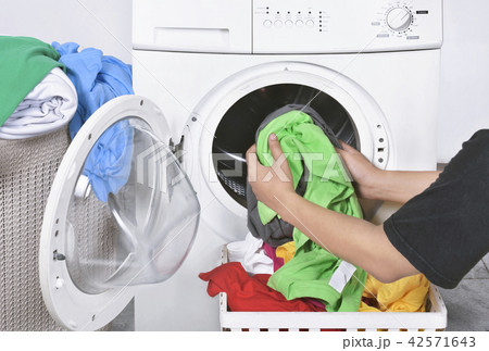 Male loading dirty clothes from basket Male loading dirty clothes from basket 42571643