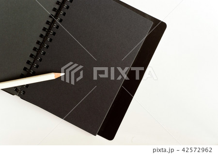 Black paper spiral notebook and white pencil 42572962
