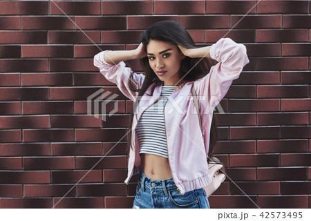 Young woman in pink jacket stading isolated on wall touching hai Young woman in pink jacket stading isolated on wall touching hai 42573495