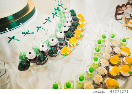 Delicious and tasty dessert table with cupcakes shots at reception closeup 42575271