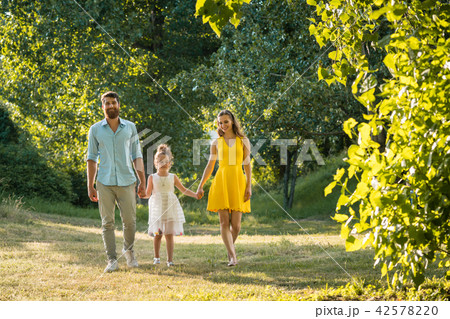 Caring parents holding hands of daughter while walking together  42578220