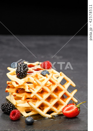 Photo of viennese wafers with berries pouring honey on black background Photo of viennese wafers with berries pouring honey on black background 42578511