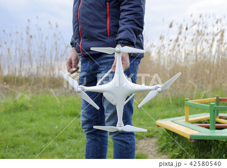A man with a quadrocopter in his hands. A white drone is being prepared for the flight. Phantom. A man with a quadrocopter in his hands. A white drone is being prepared for the flight. Phantom. 42580540