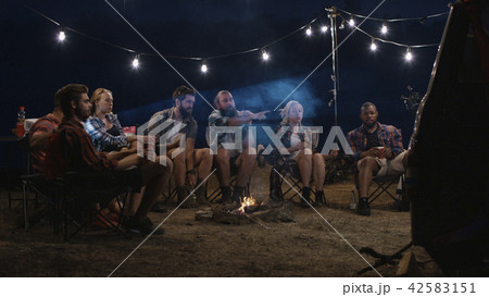 Young people watching movies near campfire 42583151
