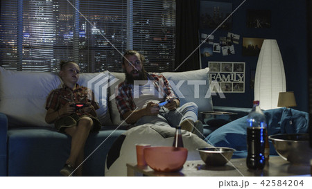 Playful father and son having fun and playing videogame 42584204