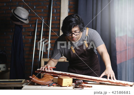 Asian Carpenter Working in Woodworking Workshop 42586681