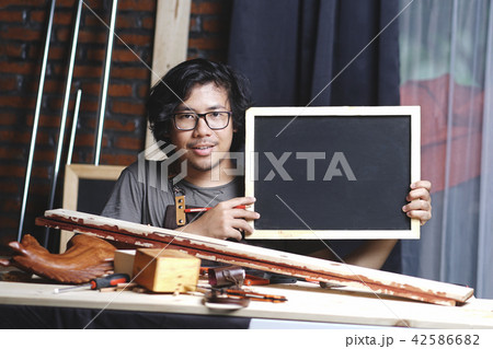 Asian Carpenter Working in Woodworking Workshop 42586682