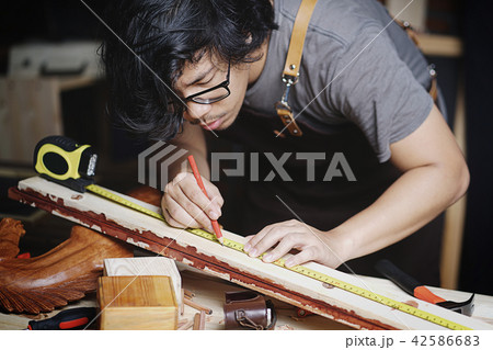 Asian Carpenter Working in Woodworking Workshop 42586683