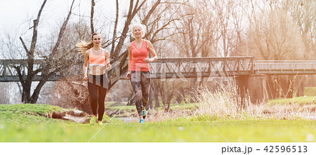 Senior and young woman running as sport on a meadow in spring 42596513