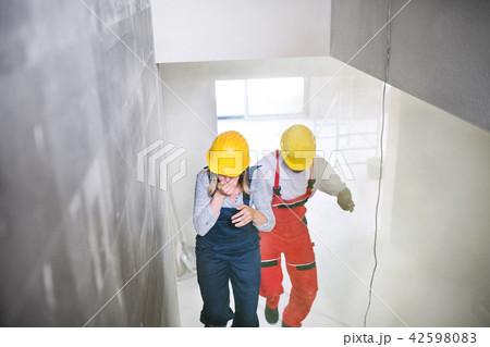 Woman and man workers running up the stairs at the construction site. 42598083