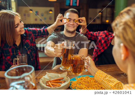 people, leisure, friendship and communication concept - happy friends drinking beer, talking and 42601041