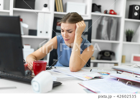 A young girl sits in the office at a computer desk and propps her hand on her head. A young girl sits in the office at a computer desk and propps her hand on her head. 42602535