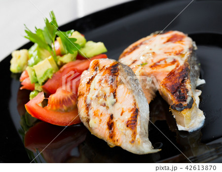 Grilled salmon with tomatoes, avocado on black dish Grilled salmon with tomatoes, avocado on black dish 42613870