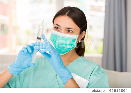 Girl nurse in mask holding syringe for injection in clinic 42615864