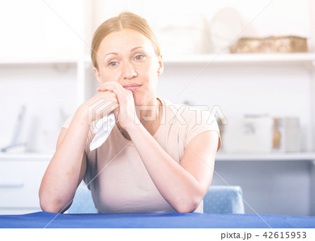 Disappointed woman sitting at table Disappointed woman sitting at table 42615953
