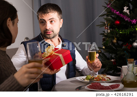 Couple celebrating New Year, woman giving present to man Couple celebrating New Year, woman giving present to man 42616291