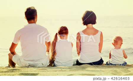 Man and woman with kids sitting with back to camera on beach Man and woman with kids sitting with back to camera on beach 42616403