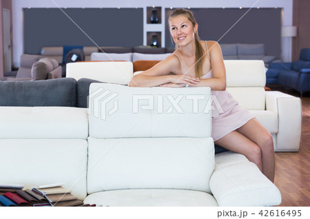 Girl customer sitting and testing new sofa Girl customer sitting and testing new sofa 42616495