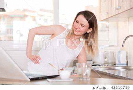 Portrait of sporty female who is standing near laptop and doing exercises 42616710