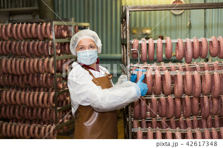 Female carrying sausages on racks Female carrying sausages on racks 42617348