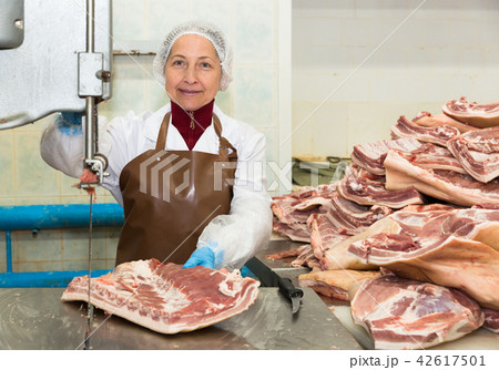 Smiling woman working on meat cutting band saw 42617501