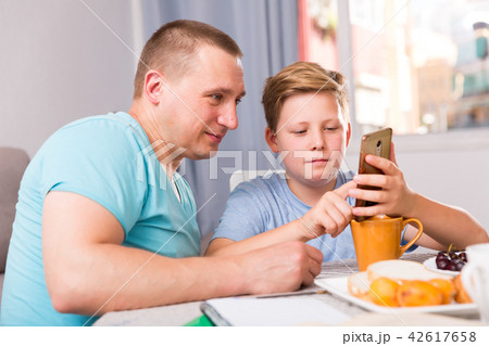 Guy with his father are resting and playing on phone Guy with his father are resting and playing on phone 42617658
