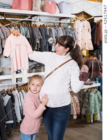 Mother and small daughter choosing clothes for baby 42617947