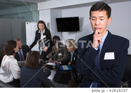 team discussing with upset Chinese man foreground team discussing with upset Chinese man foreground 42618197