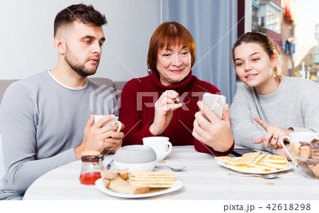 Senior woman with adult children using mobile gadget Senior woman with adult children using mobile gadget 42618298