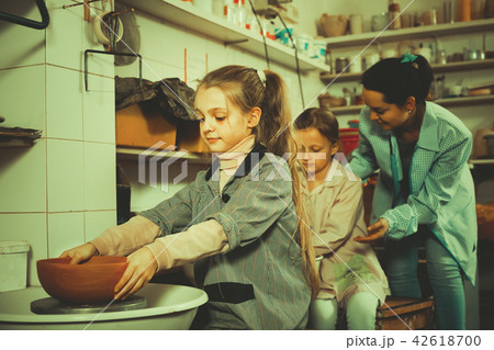 teacher helping girls to work on the potter's wheel teacher helping girls to work on the potter's wheel 42618700
