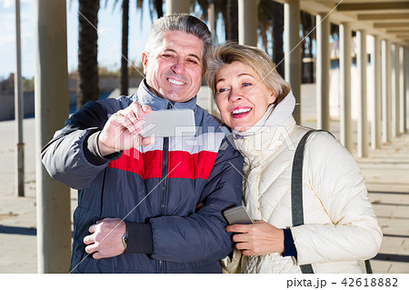 mature husband and wife make selfie on cell phones for walk 42618882