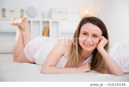 Cute girl in sleepwear lounging in bed in home interior 42619546