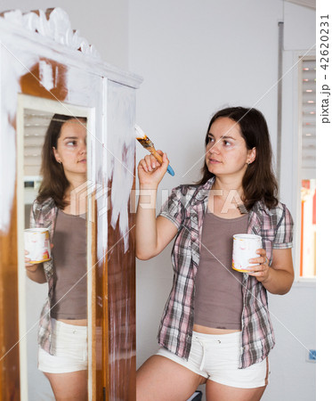 Woman is painting old cupboard in time repairs 42620231
