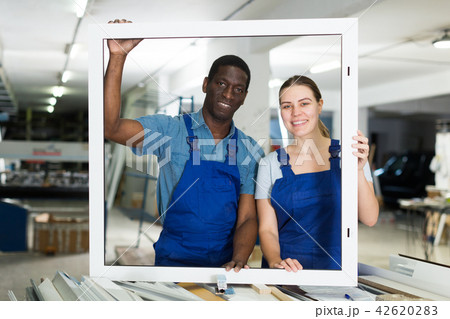 Two masters are working with window frame 42620283