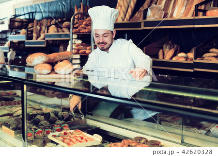 Optimistic baker showing assortment of bakery Optimistic baker showing assortment of bakery 42620328