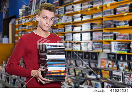 guy holding pile of boxes with DVDs guy holding pile of boxes with DVDs 42620585