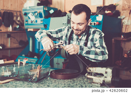 Man worker working at forming hole in belt 42620602