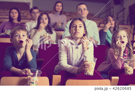 Numerous spectators eating popcorn and watching a movie 42620685