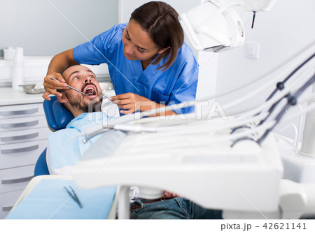 Dentist female in uniform is examinating of male in dental clinic Dentist female in uniform is examinating of male in dental clinic 42621141