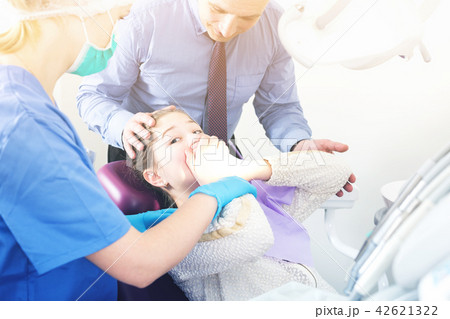 Frightened girl in dental chair refusing to open mouth 42621322