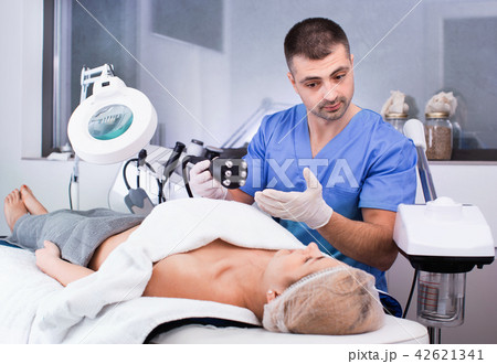 Skilled cosmetologist explaining cosmetic procedure using new equipment in clinic Skilled cosmetologist explaining cosmetic procedure using new equipment in clinic 42621341